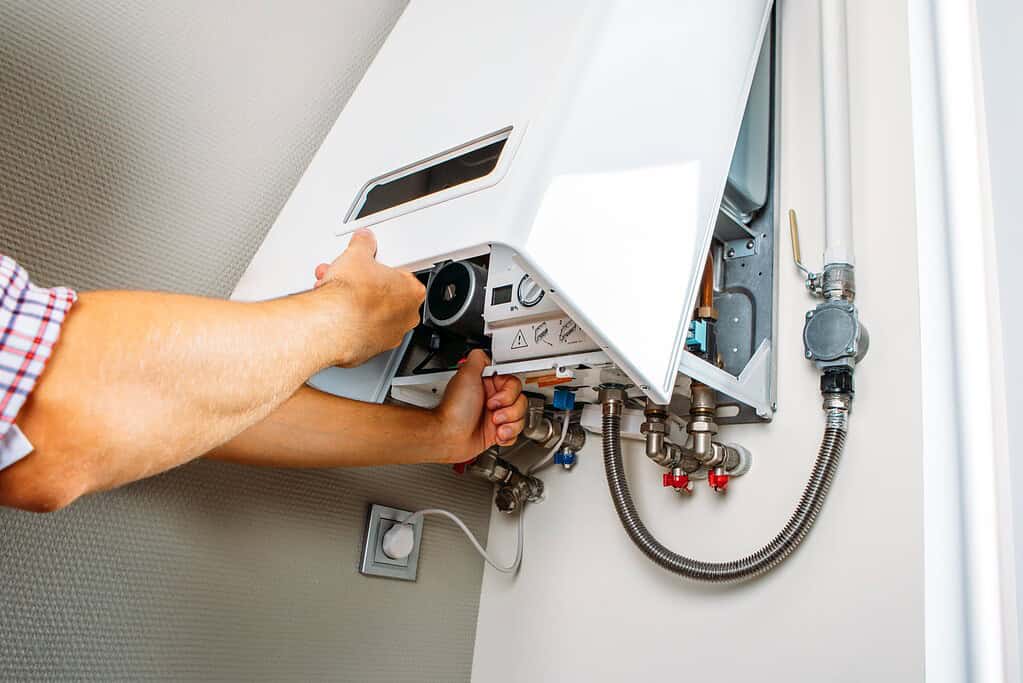 Engineer working on a boiler during a heating system repair or service.
