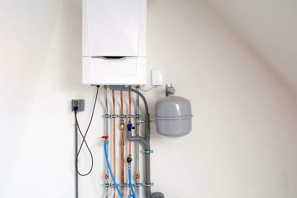 Wall-mounted domestic boiler with exposed pipes running underneath.